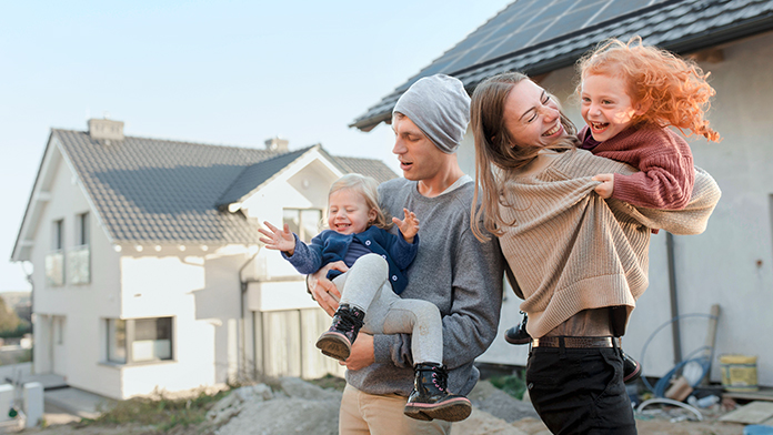 Paar mit Kindern steht auf der Baustelle des neuen Hauses