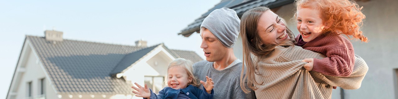 Paar mit Kindern steht auf der Baustelle des neuen Hauses