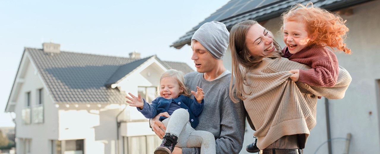 Paar mit Kindern steht auf der Baustelle des neuen Hauses