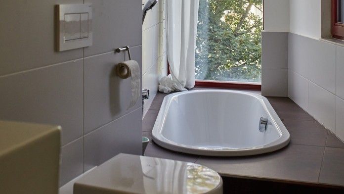 Schmales Badezimmer mit Badewanne und Blick ins Grüne