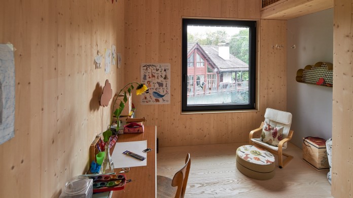 Kinderzimmer mit Schreibtisch und Sessel. Die Wände bestehen aus Fichtenholz.