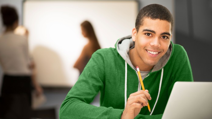 Studentin sitzt lächelnd an einem Laptopo