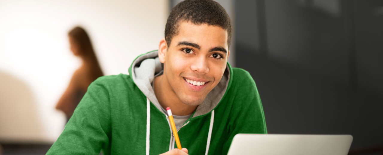 Studentin sitzt lächelnd an einem Laptop