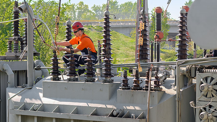 Arbeiter mit Helm bei der Reparatur von elektrischen Anlagen in einem Kraftwerk