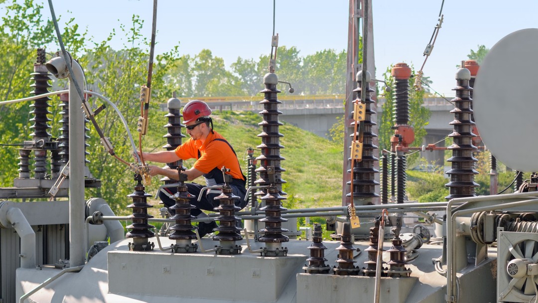 Arbeiter mit Helm bei der Reparatur von elektrischen Anlagen in einem Kraftwerk