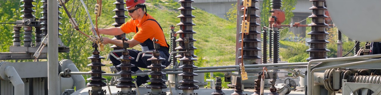 Arbeiter mit Helm bei der Reparatur von elektrischen Anlagen in einem Kraftwerk