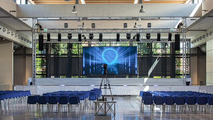 Leerer Konferenzraum, ausgestattet mit Bühne, Licht, Stühlen und professioneller Kamera