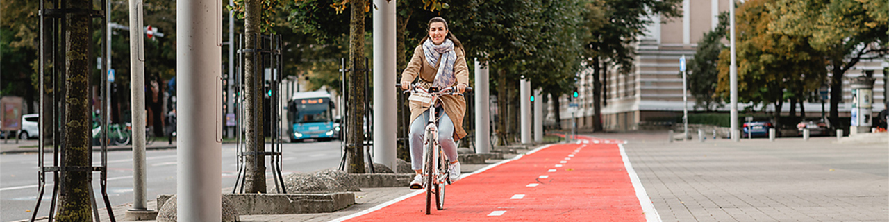 eine Frau fährt auf dem Fahrrad einen neuen Fahrradweg entlang