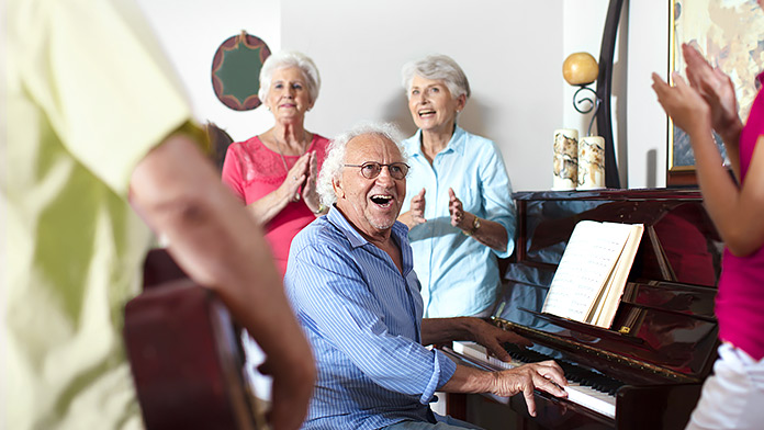 Eine Gruppe musizierender älterer Menschen, in der Mitte spielt ein Mann Klavier