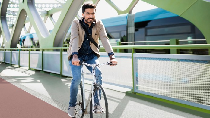 Mann fahert auf dem Fahrrad einen Fahrradweg entlang