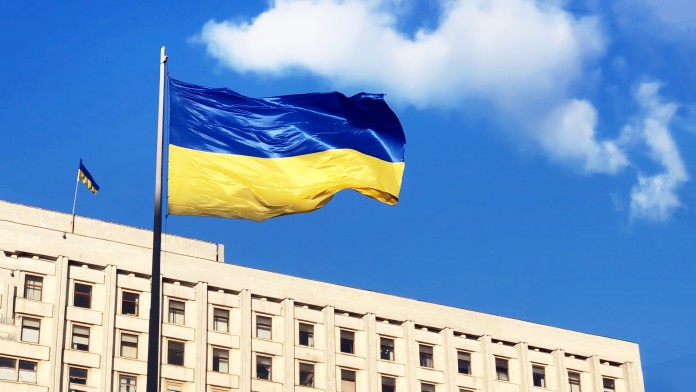 The Ukrainian flag flies in the foreground of the Central Election Commission building in Ukraine.