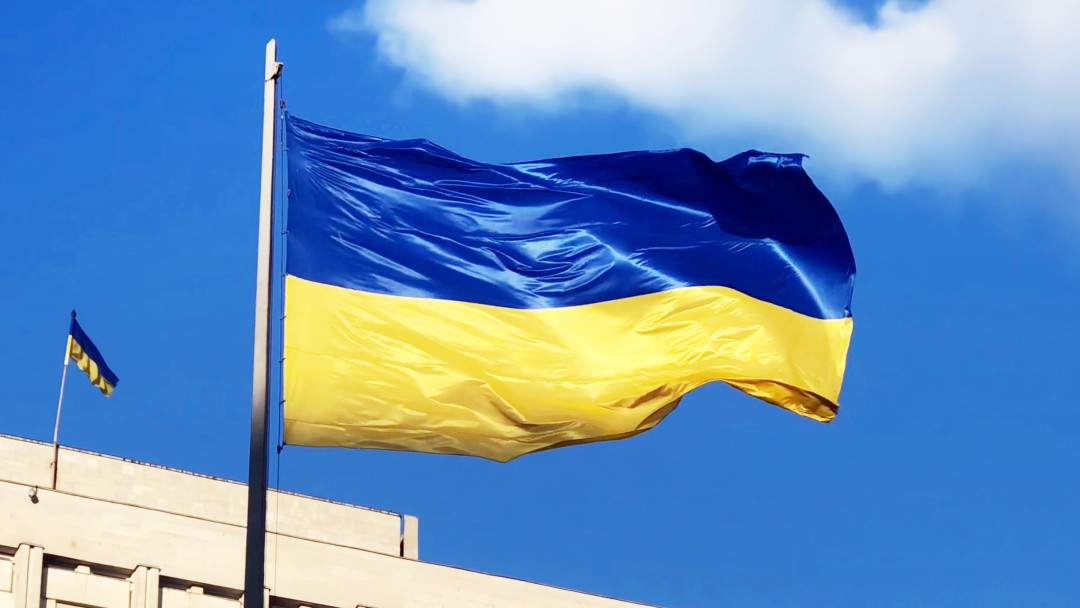 The Ukrainian flag flies in the foreground of the building of the Central Election Commission in Ukraine.