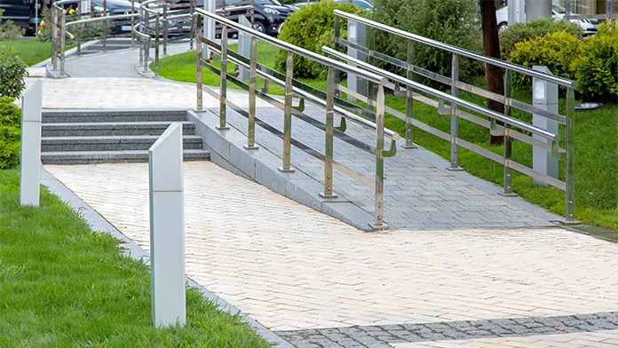 Steinrampe mit Eisengeländer in einem Stadtpark für barrierefreie Mobilität