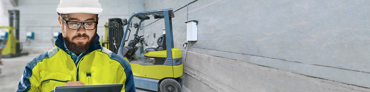Bauarbeiter arbeitet an einem Tablet, Gabelstapler im Hintergrund