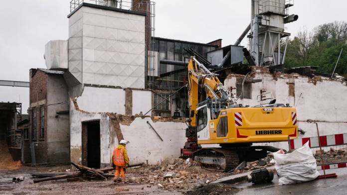 Baustelle an einem Gebäude mit Bagger und Bauarbeiter