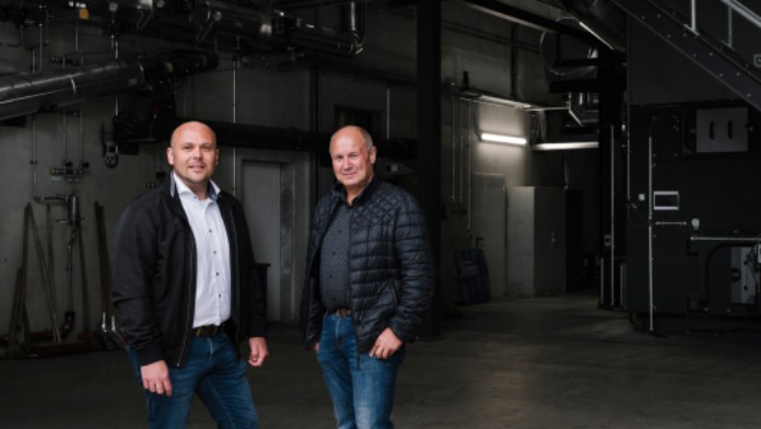 Zwei Herren stehen in einer dunklen Fabrikhalle