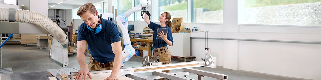 EIn Mann und eine Frau arbeiten in einer Werkstatt an Robotern