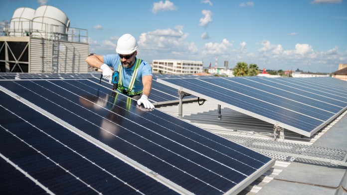 Zwei Bauarbeiter installieren eine Solarzelle auf dem Dach.