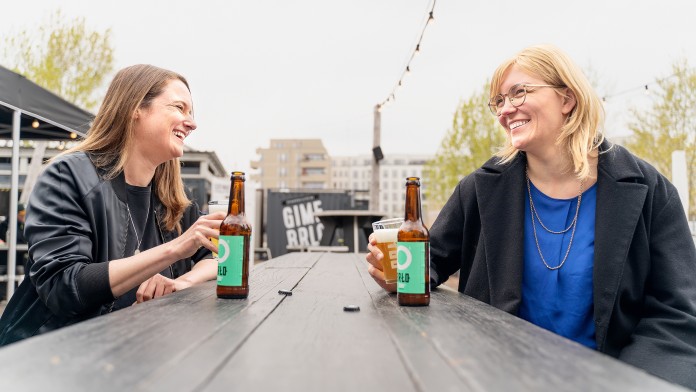 Zwei Frauen sitzen mit einem Getränk an einem Tisch