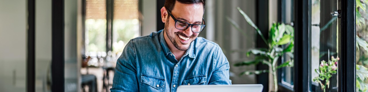 Lächelnder Mann schaut auf einen Laptop