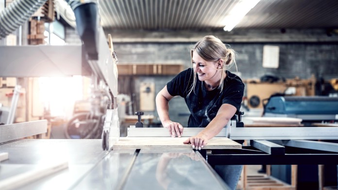 Eine blonde Frau arbeitet in einer Schreinerwerkstatt