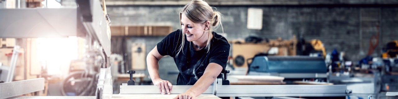 Einer blonde Frau arbeitet in einer Schreinerwerkstatt