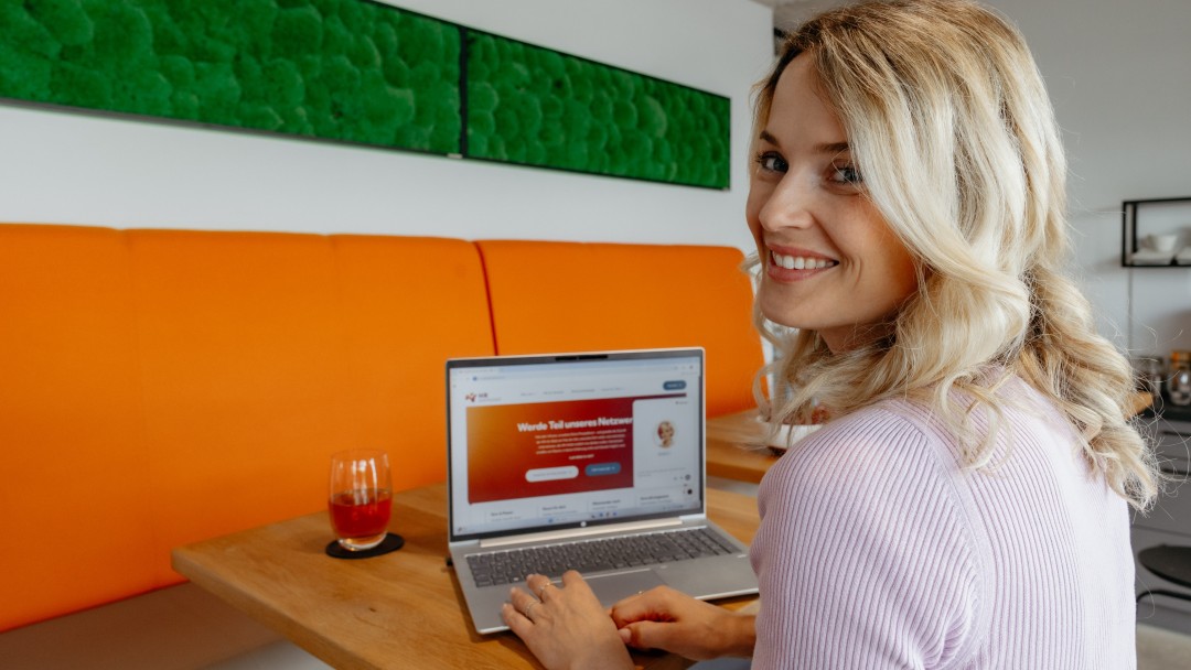 Mitarbeiterin sitzt an einem geöffneten Laptop und arbeitet mit dem KI-Voice-Agenten Nora