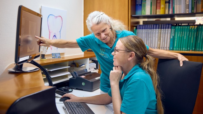 Zahnmedizinische Fachassistentinnen bei der Begutachtung einer Patientenakte