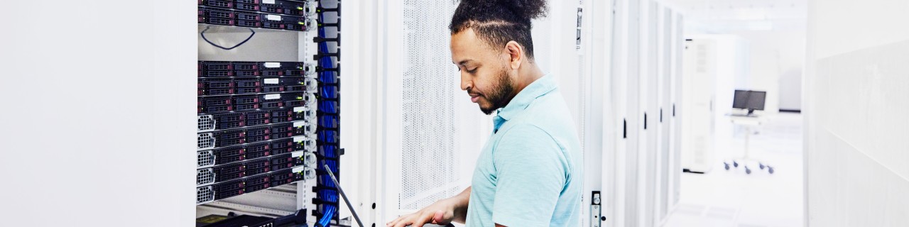 IT-Fachmann, der auf einen Laptop schaut, während er an einem Server im Rechenzentrum arbeitet