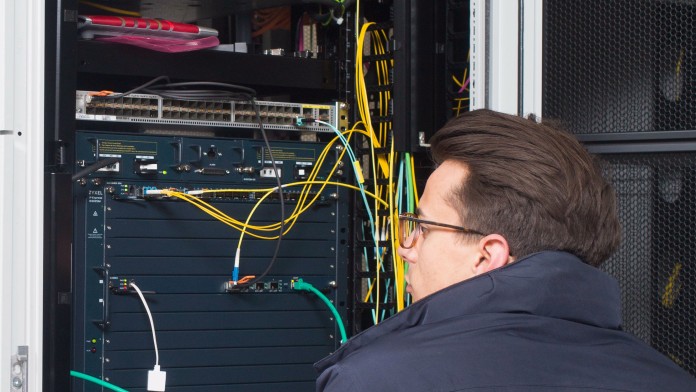 Ein Mitarbeiter kontrolliert die Verteilerstation des Glasfasersignals