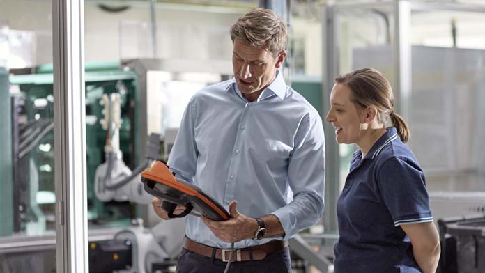 Ein Mann und eine Frau nehmen neue Einstellungen an einer Produktionsanlage vor