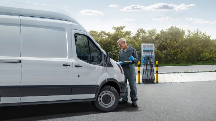 Ein Mann und ein Transporter stehen vor einer Ladestation für Elektrofahrzeuge