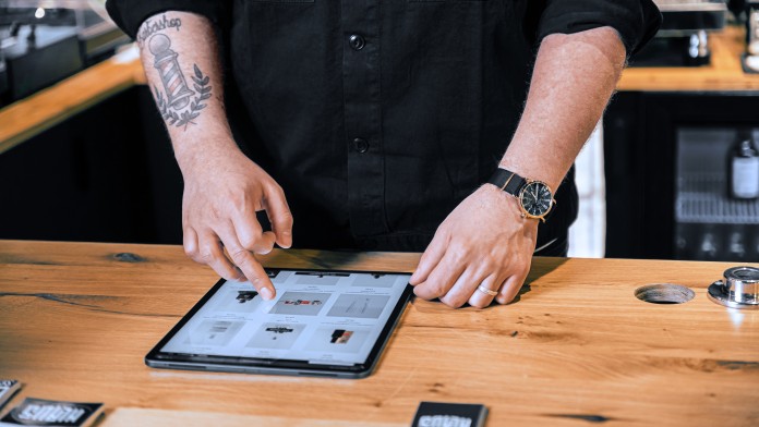 Ein Mann bedient ein auf dem Tresen liegenden iPad