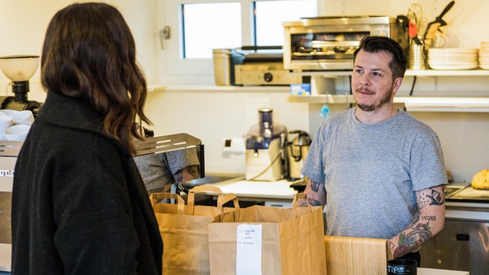 Marie Kotte und Tristian Garret unterhalten sich über den Tresen ihres Cafés hinweg