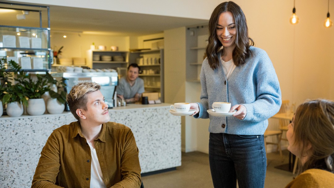 Eine junge Frau bedient Kunden in einem Café