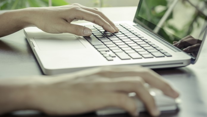 Frau arbeitet mit einer Maus und einer Tastaur an einem Computer