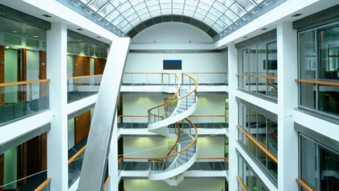 Innenansicht der Ostarkade der KfW-Niederlassung in Frankfurt. Erhöhte Perspektive auf eine Wendeltreppe. Oben ist ein gewölbtes Glasdach.