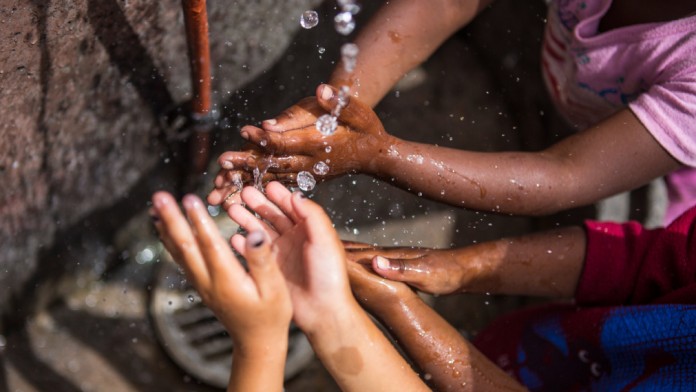 Children hold their hands under water.