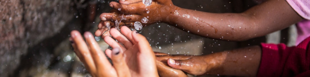 Detailaufnahme von Kinderhänden unter fließend Wasser.