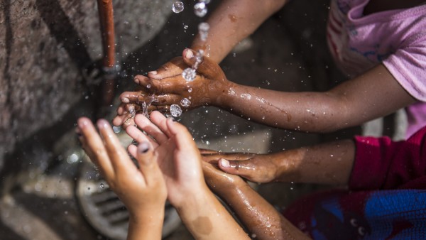 Kinderhände fangen fliessendes Wasser in Township Flamingo Heights auf