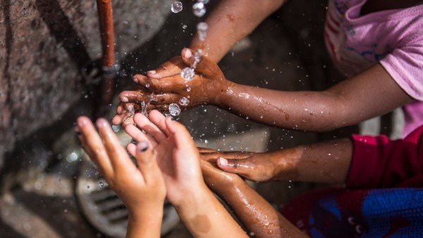 Kinderhände fangen fliessendes Wasser in Township Flamingo Heights auf