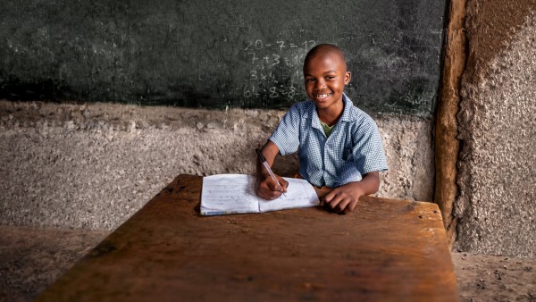 Boy from Africa sitting in front of a blackboard