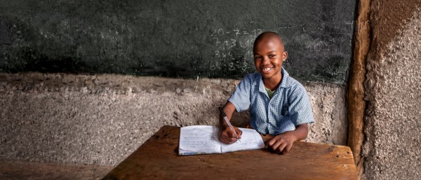 Boy from Africa sitting in front of a blackboard
