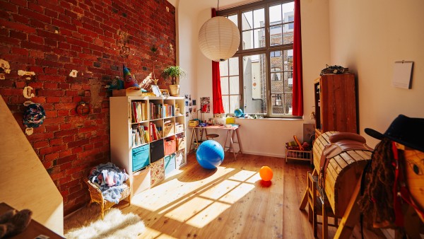 Kinderzimmer mit nackter Backsteinwand und hohen Fenstern