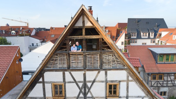 Ein Paar steht auf dem Balkoneines Fachwerkhauses