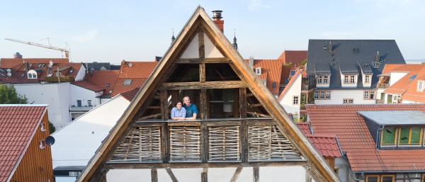 Ein Paar steht auf dem Balkoneines Fachwerkhauses
