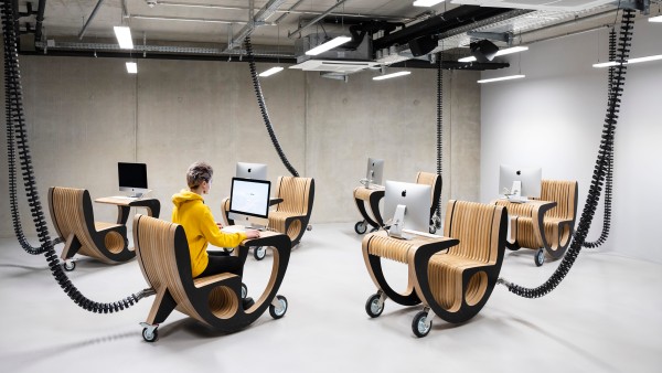 Young teacher sitting at mobile computer in TUMO Center Berlin