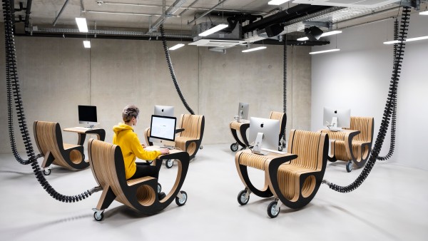 Young teacher sitting at mobile computer in TUMO Center Berlin