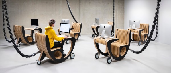 Young teacher sitting at mobile computer in TUMO Center Berlin