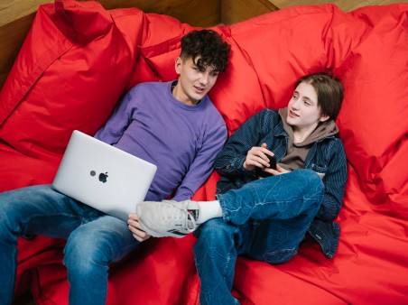 Two teenagers on a beanbag with notebook